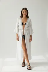 Kimono largo blanco, de manga tres cuartos, con detalle de encaje en el borde del escote profundo y en la cintura.