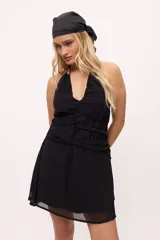 Minivestido negro con escote halter, espalda descubierta, cintura drapeada y falda con transparencias.