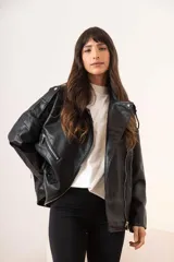 Cazadora negra de cuero sintético estilo biker, con cuello solapa, cierre cruzado con cremallera, bolsillos laterales con cremallera y trabillas en los hombros.