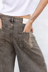 Jean de mujer color gris con efecto acid wash, de corte recto y tiro alto. Incluye bolsillos traseros y etiqueta de marca blanca en la cintura.