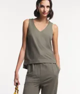 Musculosa verde oliva de piquet con escote en pico, breteles anchos, pequeñas aberturas laterales y bajos con pespuntes.