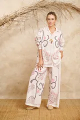 Conjunto de camisa de manga larga con cuello y pantalón palazzo, ambos con estampado de flores y hojas en tonos rosa, gris y marrón sobre fondo blanco.