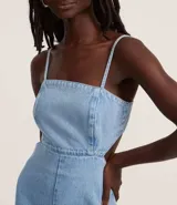 Mono largo de jean celeste con breteles finos ajustables, escote cuadrado, recortes delanteros y laterales abiertos, lazo en la espalda y elástico en la cintura.