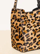 Cartera tote de cuero con estampado animal print, detalles en cuero vacuno y forrería de cuero. Incluye sobre desmontable con cierre y apliques metálicos con logo de la marca.
