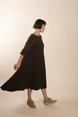 Vestido largo debajo de la rodilla, acampanado, color marrón, con cuello bote, bolsillos en el corte y mangas 3/4.