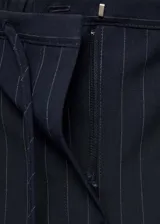 Pantalón de vestir azul marino con finas rayas verticales blancas, corte recto, tiro medio, lazo a la cintura y cierre de gancho y cremallera.