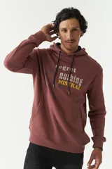 Canguro de felpa color ladrillo con capucha y cordones ajustables. Estampado frontal con la frase "Regret nothing" y logo de la marca Mistral.