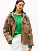 Campera marrón de Tommy Hilfiger con capucha con cordón ajustable, cierre de cremallera oculto con botones a presión, dos bolsillos delanteros tipo sobre con botón, logo metálico en el puño y corte amplio.