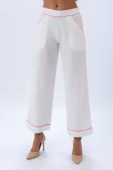 Pantalón blanco de lino y algodón, de corte palazzo, con cintura elastizada y bolsillos laterales. Presenta detalles de ribete en color coral en la cintura, bolsillos y ruedo.