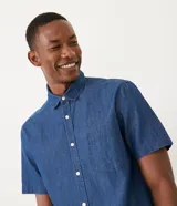 Camisa de manga corta confeccionada en tejido de algodón color azul denim, con cuello camisero, cierre frontal abotonado, bolsillo de parche en el pecho y corte comfort.