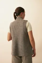 Chaleco color beige, entallado, con solapa, bolsillos plaqué y terminaciones envivadas.