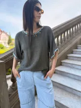 Remera tejida color marrón con hilado 100% algodón y cintas de piedras aplicadas en cuello y mangas.