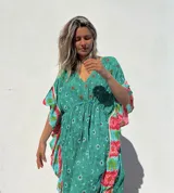 Túnica corta verde con estampado de flores rojas y detalles bordados. Mangas anchas con terminación en volados con estampado floral en tonos rosa y celeste.