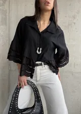 Camisa negra de mangas cortas con detalle de encaje en mangas y ruedo.