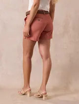 Short de jean azul oscuro con pretina con pasadores, botón y cierre. Delantera con bolsillos. Botón en bolsillos traseros. Incluye cinturón trenzado marrón con hebilla redonda dorada.