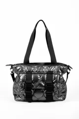 Cartera tipo tote bag color gris oscuro brillante, con diseño acolchado y correas de tela negras. Incluye dos correas frontales decorativas con hebillas de plástico negras y una correa lateral ajustable.