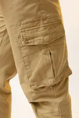 Pantalón cargo color beige, de corte ajustado, con bolsillos laterales con fuelle y cierre de botón a presión.