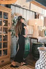 Vestido largo de tejido acanalado, con diseño bicolor vertical: mitad negro y mitad beige claro. Tiene mangas cortas y escote en V.