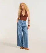 Pantalón wide leg de jeans azul claro, con cintura alta, trabillas, cierre con botón y cremallera, bolsillos y pliegues delanteros.