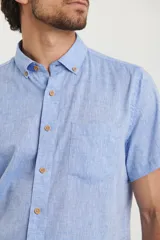 Camisa celeste de manga corta con cuello abotonado y bolsillo en el pecho.