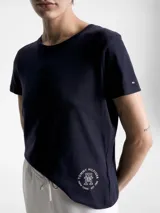 Remera azul marino de cuello redondo y manga corta, confeccionada en algodón. Presenta un logo de Tommy Hilfiger en el lateral inferior.