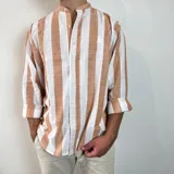 Camisa celeste y blanca a rayas verticales, de lino, con cuello mao y mangas largas con puños.