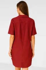 Vestido corto negro de lino, con cuello camisero, mangas cortas y cierre frontal con botones.