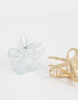 Set de dos broches para el pelo, uno dorado con forma de estrella de mar y otro transparente con forma de flor.