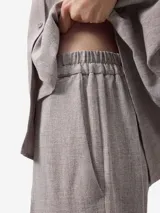 Pantalón tobillero color gris claro, de corte recto y cintura elástica. Presenta bolsillos de vivo con botón en la parte trasera.