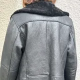 Chaqueta negra de cuero ovino con cuello y puños de piel sintética.