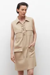 Vestido negro sin mangas con cuello camisero y cierre frontal con cordones. Presenta dos bolsillos con solapa a la altura del pecho y dos bolsillos laterales a la altura de la cadera.