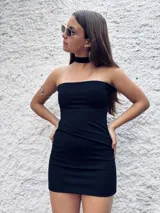 Vestido corto negro sin mangas, con corte ajustado y escote strapless. Incluye choker al cuello del mismo material. Puede usarse también con escote halter.