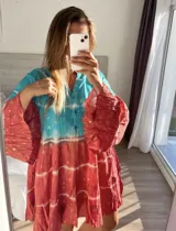 Vestido corto con estampado batik en tonos turquesa y rojo, con mangas largas acampanadas y cuello camisero.