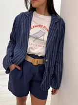 Blazer azul marino con rayas verticales blancas, confeccionado en lino italiano. Tiene botones de coco, solapas clásicas y bolsillos delanteros.