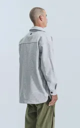 Chaqueta gris melange de paño con cuello clásico, cierre frontal con botones negros, dos bolsillos de parche en el pecho y dos bolsillos laterales.