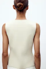 Chaleco color verde claro de punto con escote pico y cierre frontal con botones dorados.