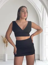 Minifalda negra con frunces laterales ajustables con cordones.