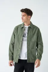Sobrecamisa verde militar de algodón grueso tipo canvas, con cuello clásico, cierre frontal con botones, dos bolsillos de parche en el pecho con solapa abotonada y dos bolsillos de parche en la parte inferior.