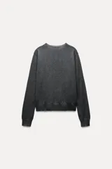 Chaqueta de punto fino color gris oscuro confeccionada con lana. Tiene cuello redondo, manga larga y cierre frontal con botones.
