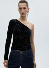 Top negro de terciopelo con un hombro descubierto, manga larga y apliques de strass.
