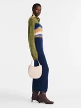 Bolso bandolera pequeño de cuero color marfil, con correa ajustable y cierre superior.
