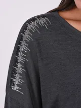 Blusa de tejido de punto color rosa viejo, con cuello redondo y mangas largas. Presenta apliques de strass en los hombros.
