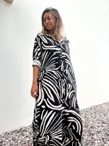 Vestido camisero largo con estampado abstracto en blanco y negro, cierre frontal con botones, mangas 3/4 y cuello camisero.