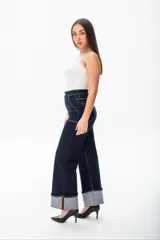 Pantalón de jean azul oscuro de corte ancho, con cintura alta, bolsillos delanteros y traseros con costuras blancas a contraste, y dobladillo ancho.