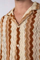Camisa de manga corta con diseño de crochet a rayas verticales en tonos beige y marrón. Tiene cuello camisero y cierre con botones.