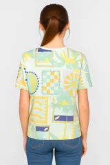 Remera amarilla con estampado de motivos playeros en blanco: soles, olas y conchas marinas.