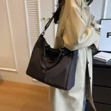 Bolso tipo tote color celeste con correa larga verde y asas cortas.