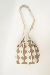 Bolso tipo bombonera tejido a crochet, con patrón geométrico en tonos rosa y marrón. Tiene cierre con cordón ajustable y correa de hombro.