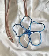 Collar con dije de flor azul hecho con alambre y cordón marrón ajustable.