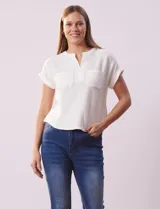 Remera blanca de tejido ribs con cuello a la base y escote en V. Tiene dos bolsillos aplicados en el frente y mangas cortas con dobladillo.